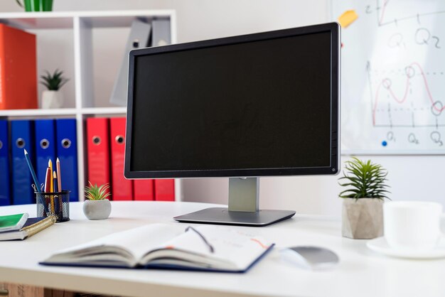 mesa de madera con computadora portátil, ordenador, monitor, bolígrafo y otra pizarra con gráficos comerciales