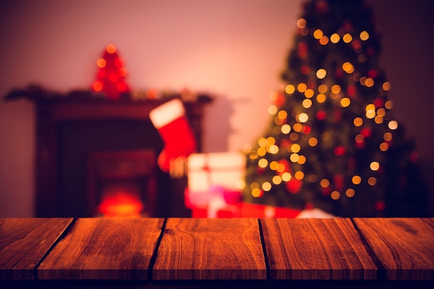 Foto mesa de madera contra el árbol de navidad con regalos cerca de la chimenea