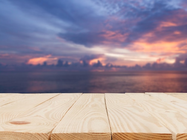 Mesa de madera delante de la vista borrosa abstracta de la luz del atardecer sobre el fondo del mar