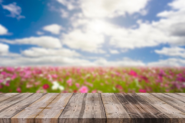 Mesa de madera en desenfoque de fondo de cielo azul y flor de cosmos