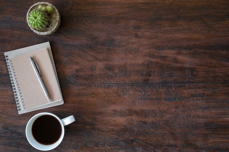 Foto mesa de madera del escritorio del inconformista de la vendimia con el cuaderno, la pluma y la taza de café.