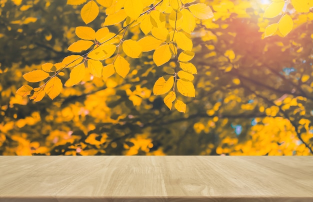 Mesa de madera y fondo de árbol y hoja de otoño borrosa