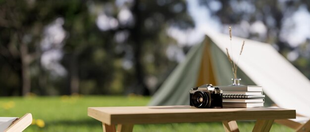 Una mesa de madera con un fondo borroso de un camping o camping en la selva con una tienda de campaña