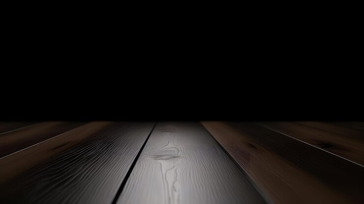 Una mesa de madera con un fondo negro y una luz sobre ella.