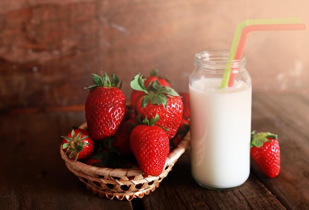 Mesa de madera con fresas y leche en un vaso.