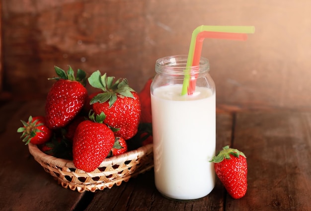 Mesa de madera con fresas y leche en un vaso.