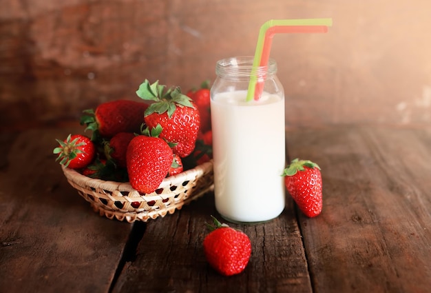 Mesa de madera con fresas y leche en un vaso.