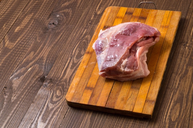 En la mesa de madera hay una oferta de carne de cerdo en una tabla.