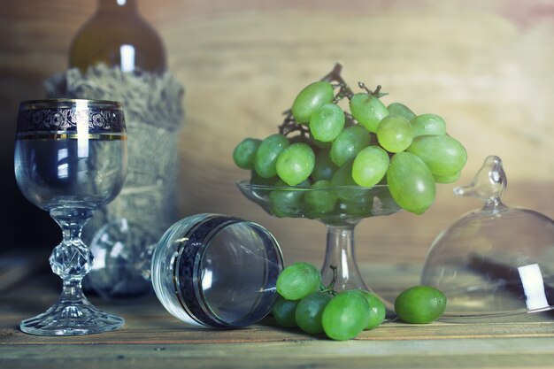 Mesa de madera con libro de botellas de vino y uva.
