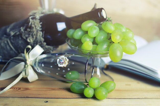 Mesa de madera con libro de botellas de vino y uva.