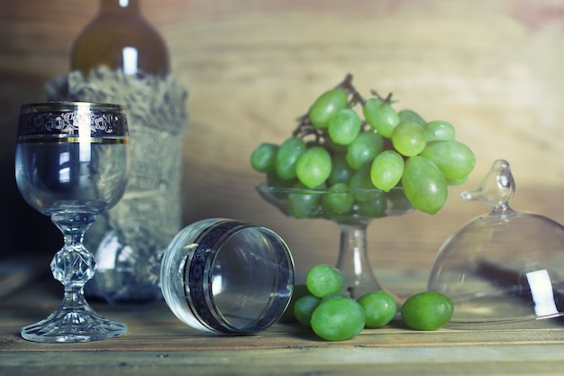 Mesa de madera con libro de botellas de vino y uva.