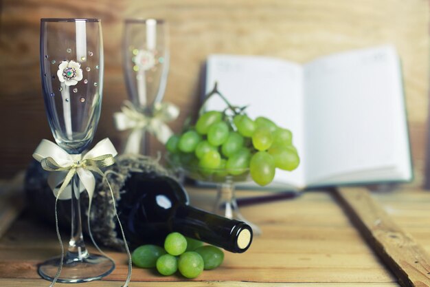 Mesa de madera con libro de botellas de vino y uva.