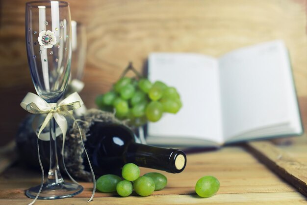 Mesa de madera con libro de botellas de vino y uva.