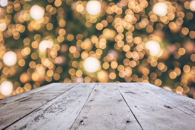 Mesa de madera con luces de bokeh festivas de vacaciones de Navidad abstractas sobre fondo borroso de árbol para exhibición de productos de montaje