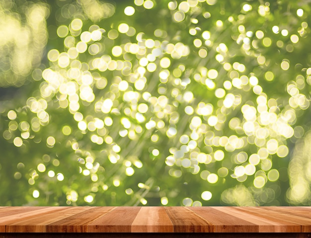 Mesa de madera marrón vacía con decoración de luz navideña borrosa en fondo de bokeh de árbol verde