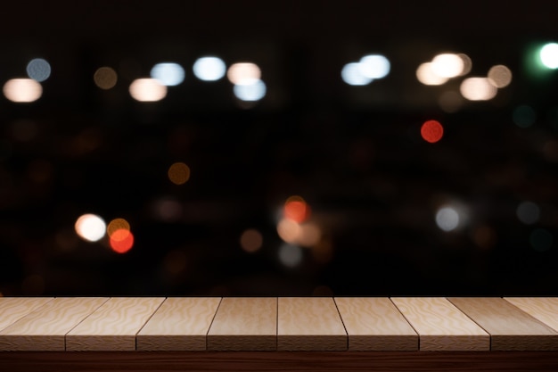 Mesa de madera marrón vacía y luz de noche bokeh borrosa restaurante fondo. Para exhibir su producto.