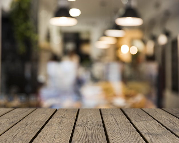 Mesa de madera mirando hacia escena borrosa de restaurante