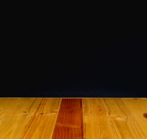 Mesa de madera o escritorio con fondo de pared negra.