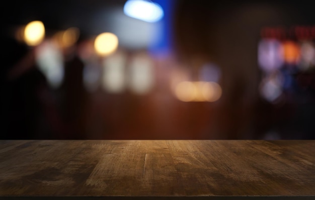 Mesa de madera oscura vacía frente a un fondo de bokeh borroso abstracto del restaurante se puede usar para mostrar o montar sus productosMock up para el espacio