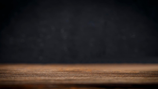 Mesa de madera en la pared negra en el fondo de la habitación oscura