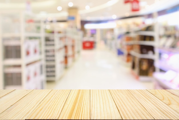 Mesa de madera con pasillo de supermercado borroso abstracto con fondo de estantes de productos