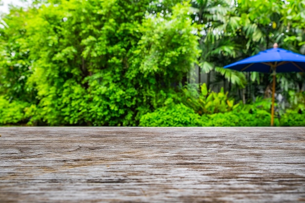 Mesa de madera en el patio del jardín verde con sombrilla azul