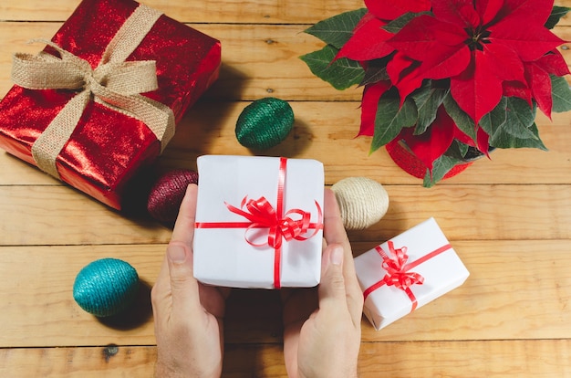 Mesa de madera con regalos de navidad y poinsettia Person manos