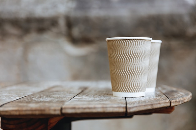 Mesa de madera rústica con vasos de papel acanalado marrón llenos de café caliente recién hecho