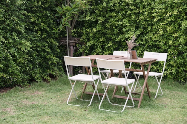 Mesa de madera con sillas y maceta en jardín ornamental en el patio trasero