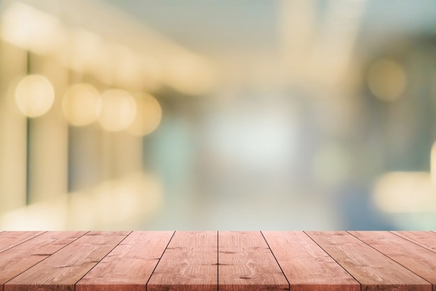 La mesa de madera vacía y la cafetería borrosa y el fondo interior restaurado se pueden usar para exhibir o montar sus productos.