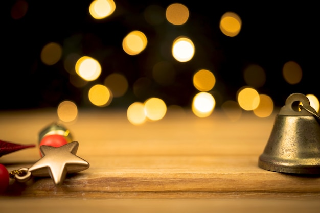 Foto mesa de madera vacía con decoración navideña, estrella dorada y campana navideña. destellos y bokeh de fondo. diseño para su foto de concepto de producto