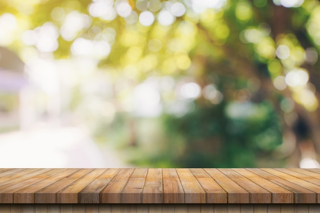 Mesa de madera vacía y desenfocado bokeh y desenfoque de fondo de árboles de jardín con luz solar. plantilla de visualización de productos.