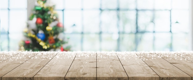 Mesa de madera vacía con desenfoque bokeh árbol de Navidad y fondo de banner de decoración de año nuevo con nevadas: se puede utilizar para exhibir o montar sus productos.