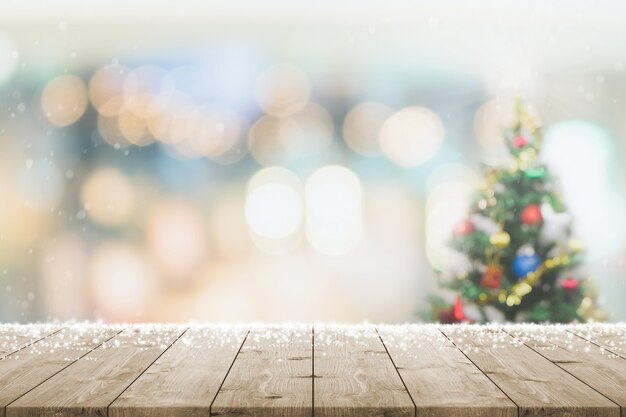 Mesa de madera vacía con desenfoque bokeh árbol de Navidad y fondo de banner de decoración de año nuevo con nieve: se puede utilizar para exhibir o montar sus productos.