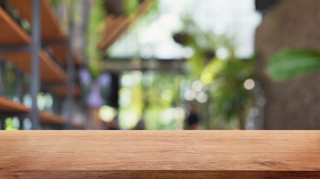 Mesa de madera vacía y fondo interior borroso de cafetería, cafetería y restaurante: se puede utilizar para exhibir o montar sus productos.