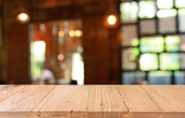 La mesa de madera vacía frente al fondo borroso abstracto de la cafetería se puede usar para exhibir o montar sus productos Maqueta para exhibir el producto