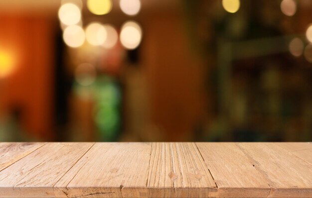 La mesa de madera vacía frente al fondo borroso abstracto de la cafetería se puede usar para exhibir o montar sus productos Maqueta para exhibir el producto