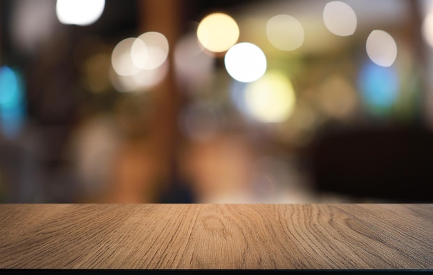 La mesa de madera vacía frente al fondo borroso abstracto de la cafetería se puede usar para exhibir o montar sus productos Maqueta para exhibir el producto