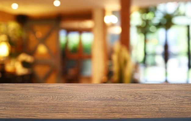 La mesa de madera vacía frente al fondo borroso abstracto de la cafetería se puede utilizar para exhibir o montar sus productos