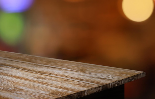 La mesa de madera vacía frente al fondo borroso abstracto de la cafetería se puede utilizar para exhibir o montar sus productos