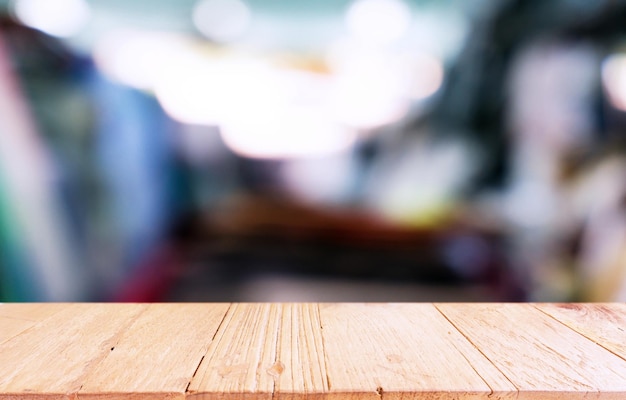 La mesa de madera vacía frente al fondo borroso abstracto de la cafetería se puede utilizar para mostrar el producto