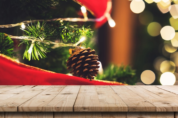 Mesa de madera vacía y piñas de Navidad que cuelgan de un árbol de Navidad con montaje de exhibición