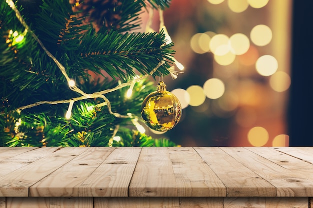 Mesa de madera vacía y piñas de Navidad que cuelgan del árbol de Navidad