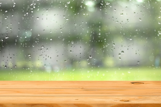 Mesa de madera vacía sobre el agua gota sobre fondo de jardín de ventana