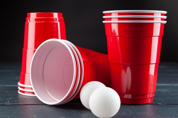 Foto mesa de madera con vasos rojos y bola para cerveza pong