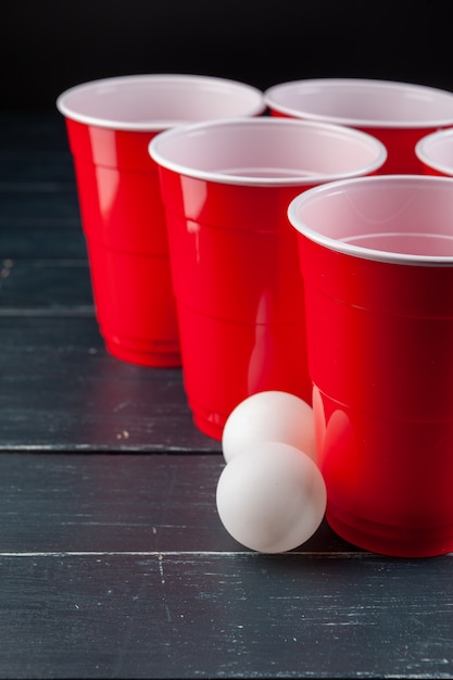 Mesa de madera con vasos rojos y bola para cerveza pong