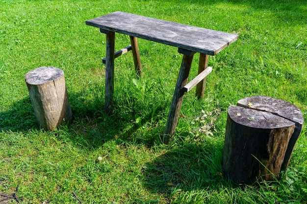 Mesa de madera vieja y troncos de árboles para sentarse en el campo.