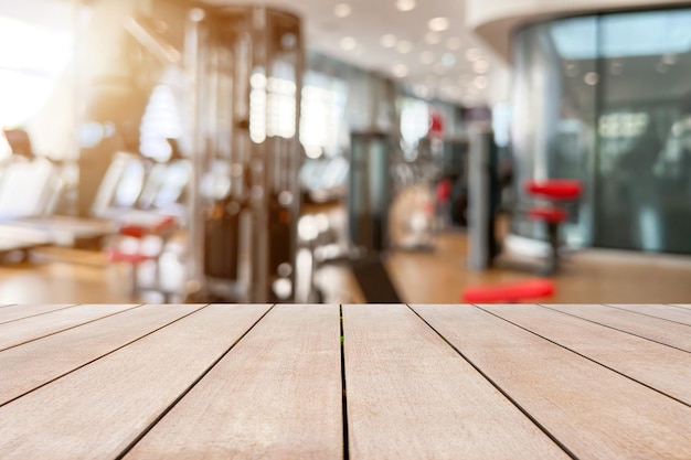 Mesa de madera vieja vacía frente al fondo borroso del equipo de gimnasio y la zona de entrenamiento con pesas de la máquina Puede usarse para exhibición o montaje para mostrar sus productos