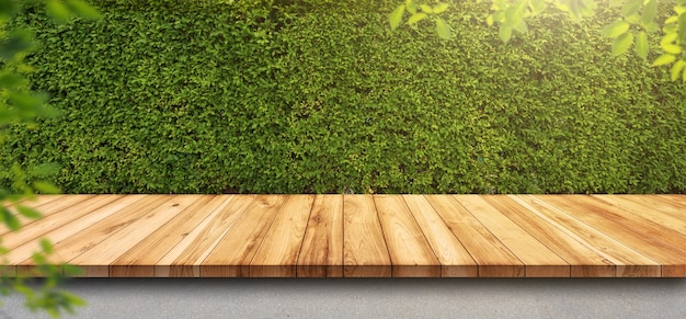 Mesa de madera vieja vacía con pared de hojas verdes