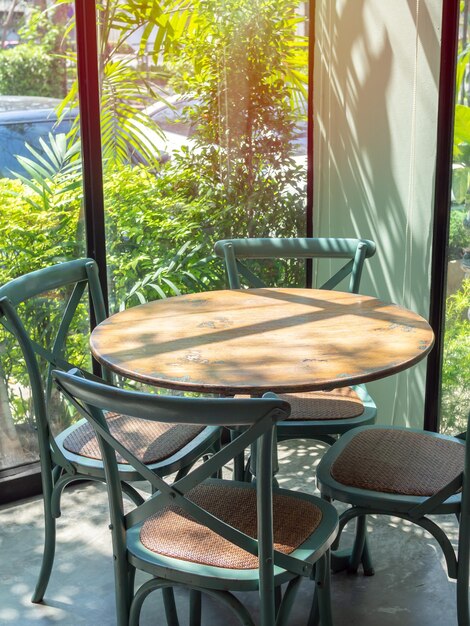 Mesa de madera vintage en sala de vidrio cerca del jardín